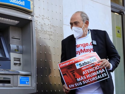 El impulsor de la campaña "Soy mayor no idiota", Carlos San Juan, posa junto a un cajero automático tras registrar 600.000 firmas en el Ministerio Economía para exigir a los bancos una mejor atención.