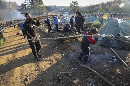 Migrantes transportan madera en el campamento de Grodno (Bielorrusia), el 10 de noviembre. Polonia declaró en septiembre el estado de emergencia en dos provincias fronterizas con Bielorrusia, una situación legal que impide el acceso de ONG para ayudar con suministros y asistencia médica.