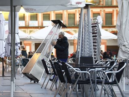 Un trabajador recoge el mobiliario de la terraza de un restaurante en el centro de Córdoba.