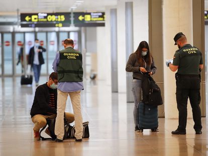 Una pareja de la Guardia Civil realiza un control a unos viajeros en El Prat durante en mayo de 2020, durante la pandemia de coronavirus.