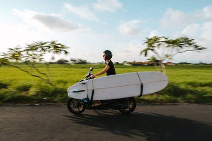 Una joven en moto con su tabla de surf, en los alrededores de Canggu (Bali, Indonesia).