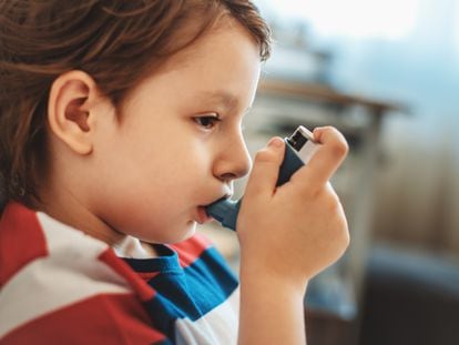 Un niño con asma usa su inhalador.