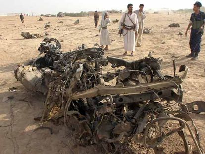 Un militar y otros hombres armados se acercan a ver los restos del coche en el que viajaban los siete turistas españoles atacados el lunes el Yemen.