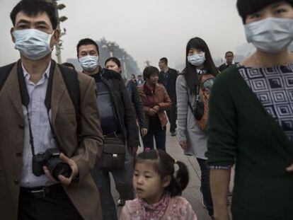 Varias personas caminan con mascarilla por la plaza de Tiananmen de Pek&iacute;n.