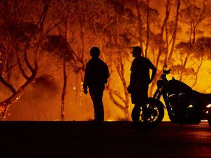 Dos residentes observan las llamas en Lake Tabourie, Australia.