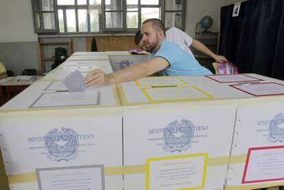 Un miembro de una mesa de votaciones en Milán deposita una papeleta.