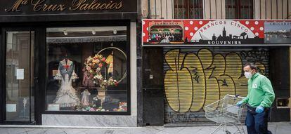 Un hombre camina junto a una tienda de trajes de flamenca que permanece cerrada. 