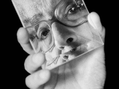 Saramago sostiene un espejo en que se refleja su rostro.