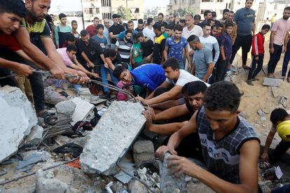 Un grupo de palestinos remueven los restos de un edificio de Jan Yunis derrumbado por las bombas israelíes en busca de víctimas.