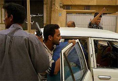 Un grupo de iraquíes armados detiene a un saqueador, al que meten en un coche, ayer en Bagdad.