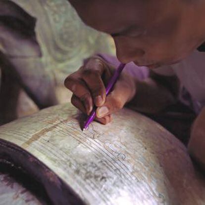 Un artesano birmano dibujando en la madera de bambú antes de lacarla.