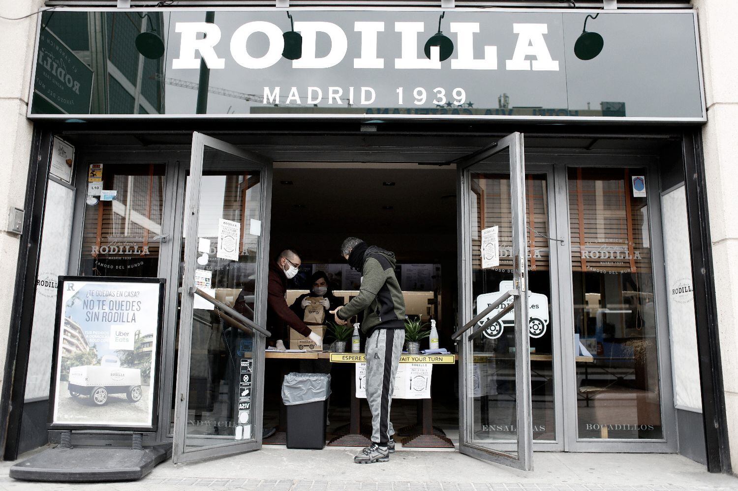 Un hombre recoge el menú para sus hijos en un establecimiento de Rodilla en Madrid.
