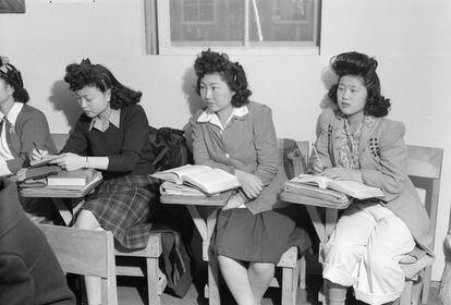Tres jóvenes sentadas en pupitres durante una clase de biología en el Centro de Reubicación de Guerra de California, 'Manzanar', en 1943.