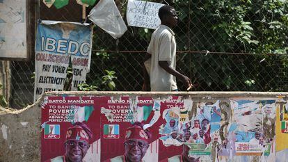 Un hombre camina junto a varios carteles electorales del recién elegido presidente del país, Bola Ahmed Tinubu, en el distrito de Agege en Lagos.