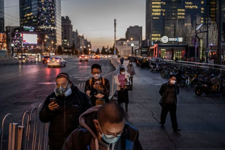 Varios ciudadanos, todos ellos con mascarilla, hacen cola para coger el autobús el pasado 20 de marzo en Pekín.