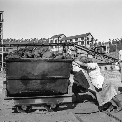 Dos trabajadoras empujan un vagón de carbón.