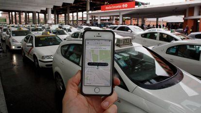 Un usuario utiliza la &#039;app&#039; de Uber junto a la parada de taxis de la estaci&oacute;n de Atocha, en Madrid.