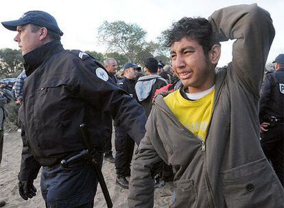 Un policía francés se lleva a un menor afgano dentro del campamento de Calais.