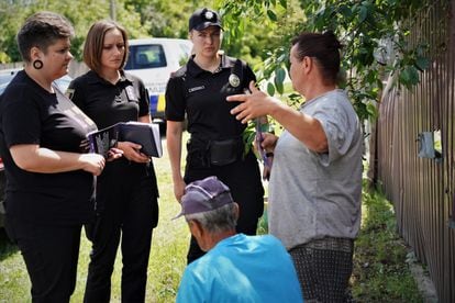 Miembros de la brigada policial móvil que lidera Olga Yuskevich (tercera desde la izquierda) conversan con algunos vecinos en una zona rural en presencia de la psicóloga Olena Shtyria (izquierda)