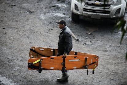 A man carries two empty stretchers as the miners remain trapped underground.