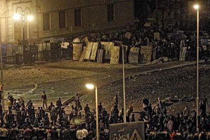 Enfrentamientos a pedradas entre los detractores de Mubarak (al fondo, tras las barricadas) y sus partidarios, en la plaza de la Liberación.