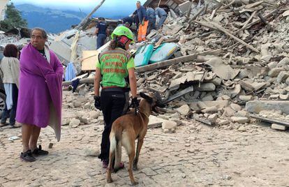 Un hombre cubierto con una manta observa a los equipos de rescate trabajando en un edificio colapsado en Amatrice.