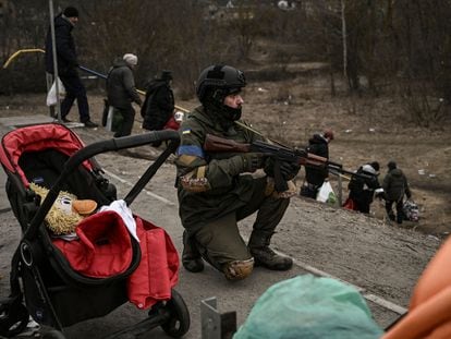 Las tropas ucranias cubren a los ciudadanos que son evacuados de la ciudad de Irpin, cerca de Kiev, el domingo.