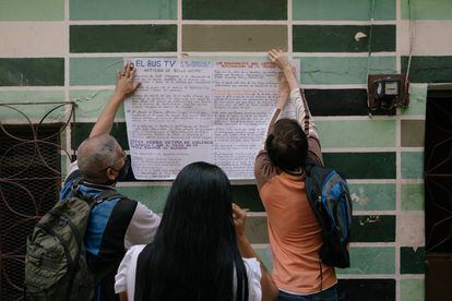 Integrantes de El Bus TV pegan un afiche con información después de dar las noticias en el barrio Bello Campo de Caracas.