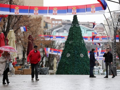 Varias personas caminan en la principal zona peatonal en el norte de Mitrovica, en Kosovo, en la que cuelgan banderas serbias, el 11 de enero.