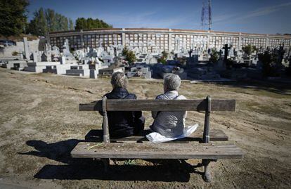 Dos mujeres descansan en un banco frente al cementerio de La Almudena de Madrid.