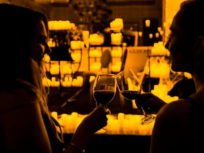 Dos personas disfrutan de unos vinos en un concierto de música clásica a la luz de las velas.