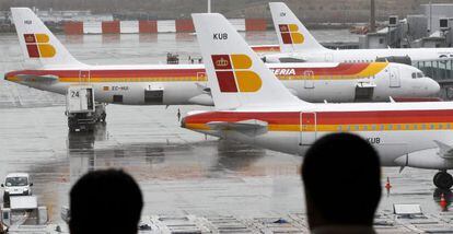 Dos pasajeros observan varios aviones de la compa&ntilde;ia Iberia en las pistas del aeropuerto de Barajas. EFE/Archivo