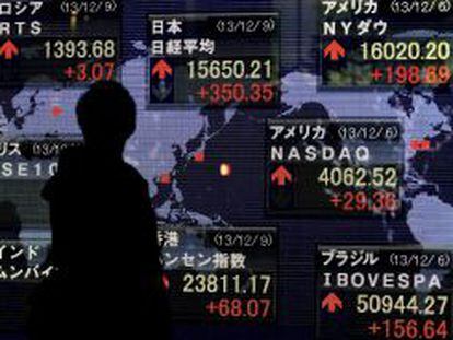 Un empresario pasa por delante de una pantalla con la cotizaci&oacute;n de la Bolsa de Tokio.