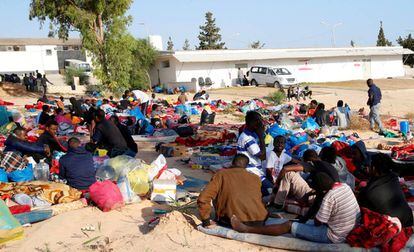 Los migrantes, con sus pertenencias, en el exterior del centro de detención bombardeado en Trípoli.