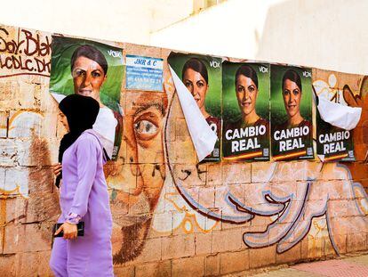 Una mujer con hiyab pasa frente a carteles electorales de Vox en El Ejido (Almería).