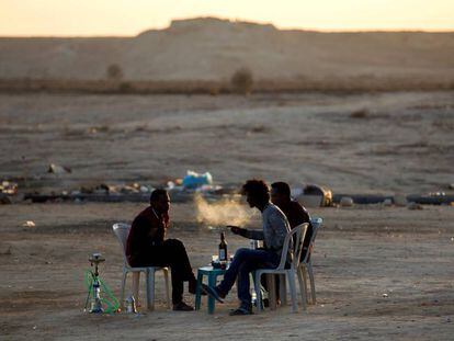 Unos refugiados eritreos fuman de pipas de agua y beben en el exterior del centro de detenci&oacute;n de Holot, en el desierto de Negev, cerca de la frontera entre Israel y Egipto.