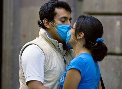 Una pareja se besa con las mascarillas puestas en México DF.