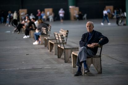 Un hombre espera sentado mientras personas votan a su alrededor.