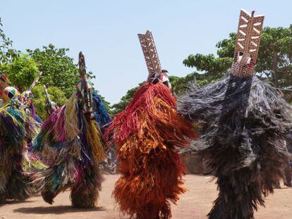 Bailarines con trajes de fibras tintadas y m&aacute;scaras de madera en el barrio de Kibide, en Bobo Dioulasso.