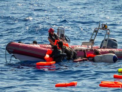 Un miembro de la tripulación del barco de Open Arms ayuda a dos migrantes a subir a una lancha de rescate tras el naufragio de la patera.