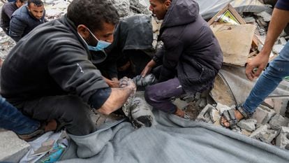 Ciudadanos palestinos trabajan para rescatar el cadáver de un niño de entre los escombros de un edificio destruido por ataques israelíes en Rafah este viernes.