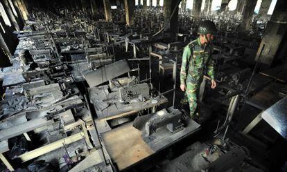 Un polic&iacute;a inspecciona unos talleres de confecci&oacute;n de ropa tras incendiarse en Dacca (Bangladesh), el pasado noviembre.