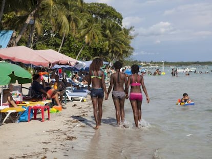 Tres jóvenes pasean por la playa de Boca Chica.