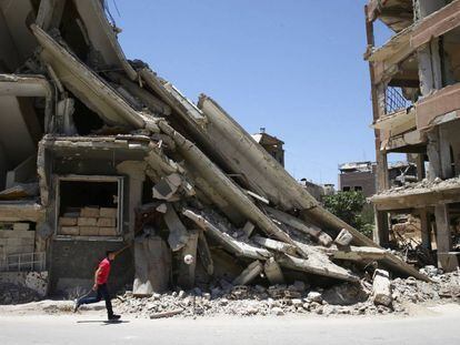 Un ni&ntilde;o juega frente a un edificio destruido en Damasco.