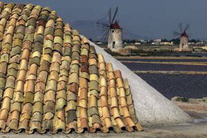 Molinos y montañas de sal cubiertas con tejas de terracota en Trapani, Sicilia (Italia).