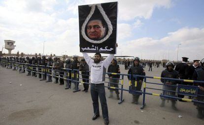 Un detractor del expresidente egipcio Hosni Mubarak, sostiene una pancarta donde se puede leer &#039;veredicto del pueblo&#039;, frente a la Academia Policial donde hoy, se ha reanudado el juicio en El Cairo (Egipto)