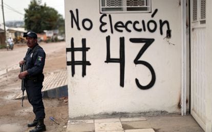 Un policía en Guerrero (México) junto a una pintada por el boicot electoral.
