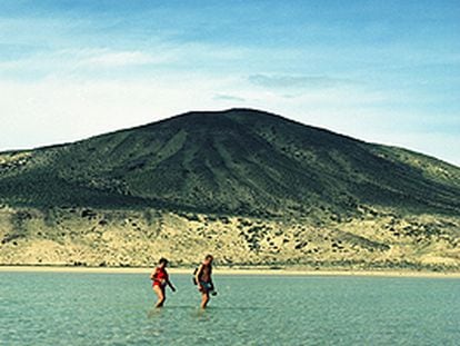 Una pareja cruza una laguna natural que la marea suele formar en la playa de sotavento de la península de Jandía, en Fuerteventura.