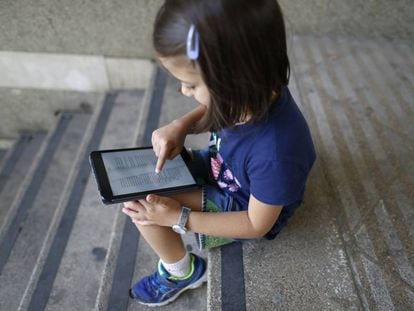 Una niña lee en una tableta digital.