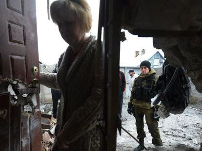 Un miliciano prorruso observa como una mujer entra en su casa tras ser alcanzada por el bombardeo, a las afueras de Donetsk.